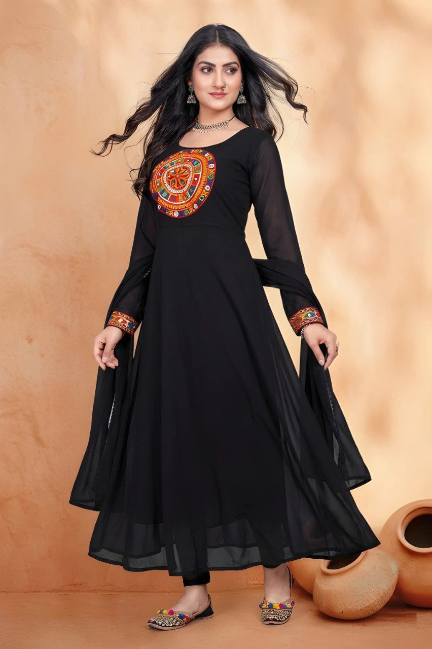 Woman wearing a black dress with orange embroidery against a beige background
